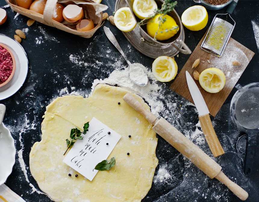 Dough and flour next to lemons and rolling pin