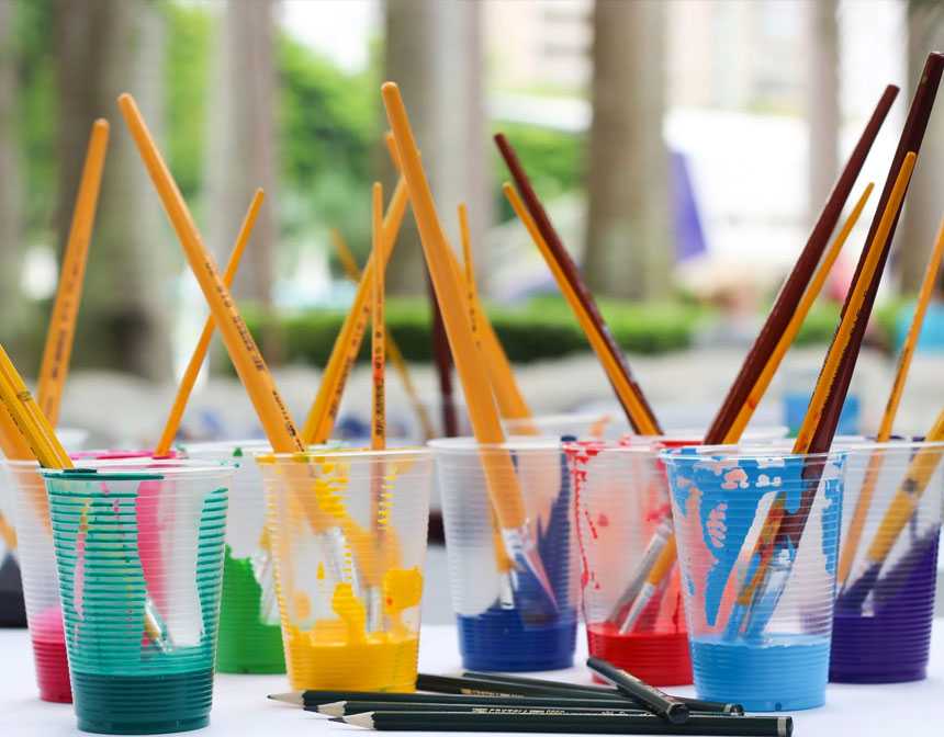 Paintbrushes and paints in plastic cups