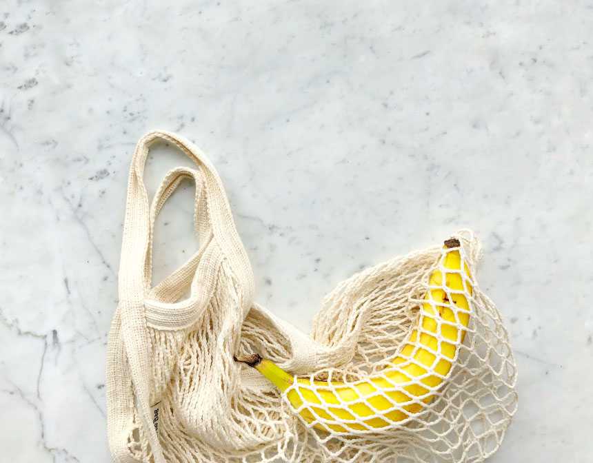 Ripe banana in white knitted bag